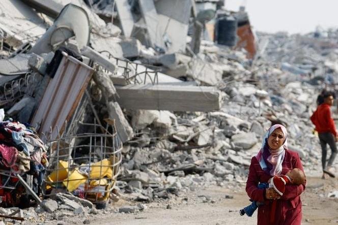 Seorang wanita Palestina dan bayinya di jalan yang hancur di Gaza, 2 November 2025.