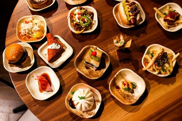 Pilihan hidangan gourmet disajikan di atas meja kayu, masing-masing disajikan dengan indah di piring hias kecil. Keberagaman 