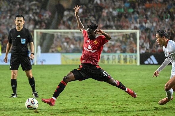 Selama pertandingan sepak bola, seorang pemain berseragam merah melompat ke udara dan mencoba memukul bola sementara pemain lain di a Selama pertandingan sepak bola, seorang pemain berseragam merah melompat ke udara dan mencoba memukul bola sementara pemain lain di a